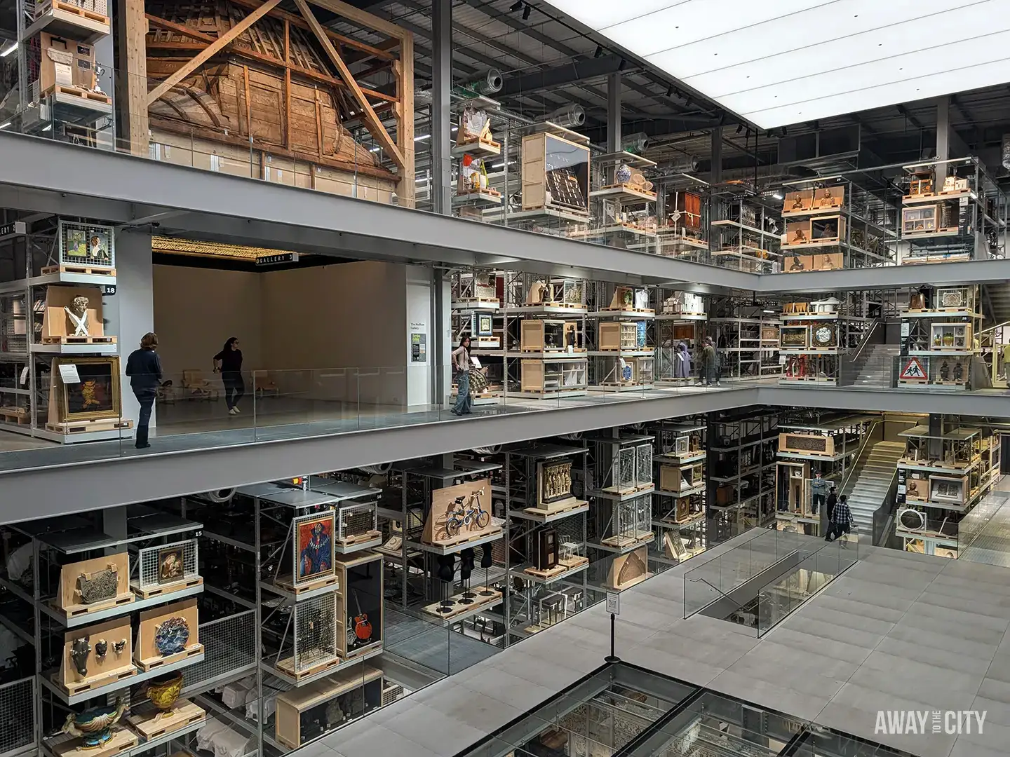 The massive, multi-level interior of the V&A East Storehouse in London, featuring rows of archived museum collections in open storage units.