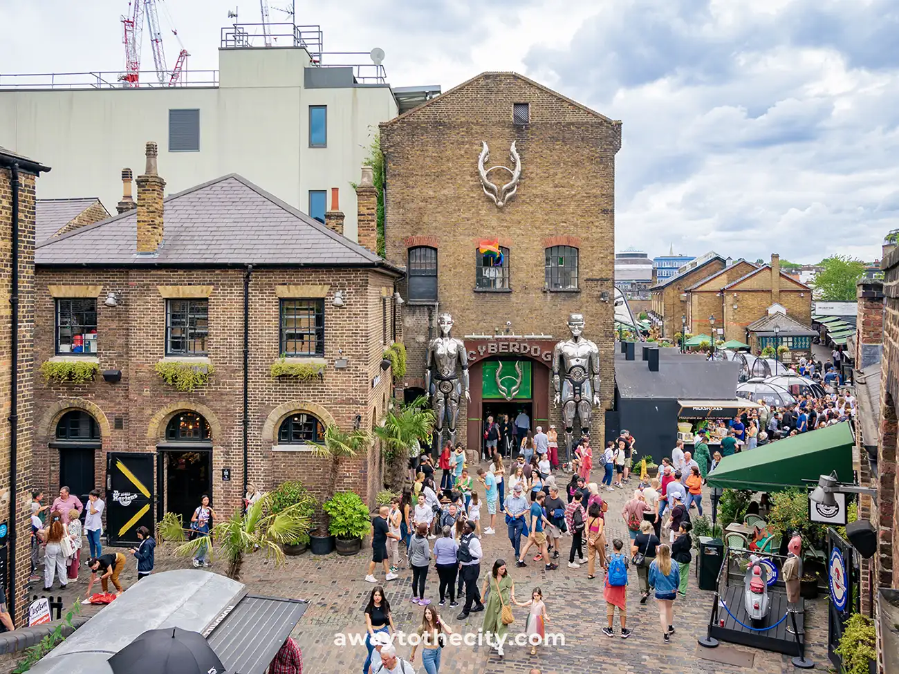 The entrance to Cyberdog shop in Camden Market features two large robot statues and a bustling crowd.