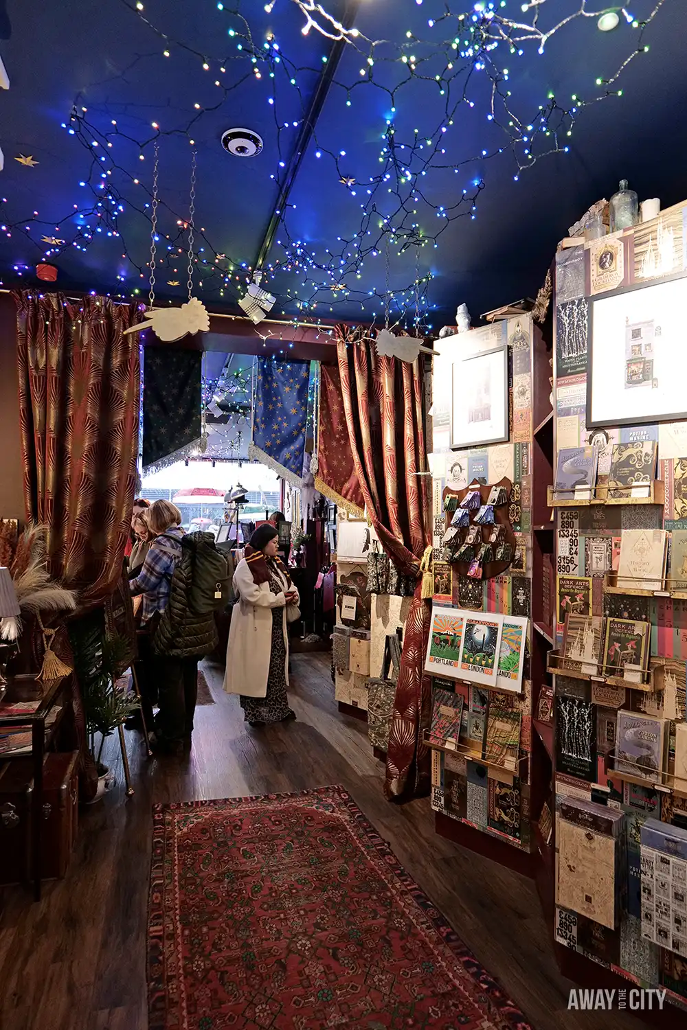 The House of MinaLima is decorated with string lights, burgundy curtains, and numerous posters and prints on the walls.