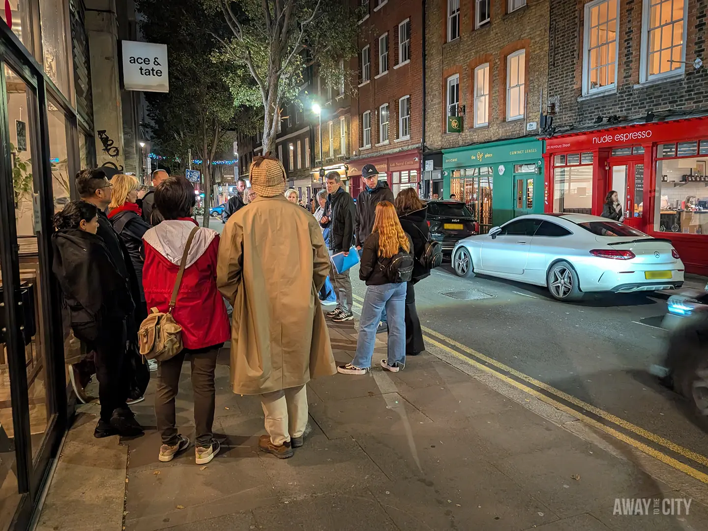A group of people take part in a Jack the Ripper walking tour in London.