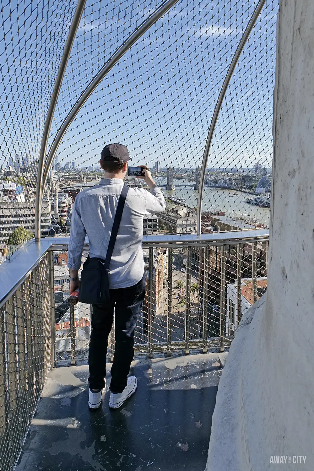 A view from the Monument to the Great Fire of London shows a man taking a picture of the River Thames from the caged observation platform.