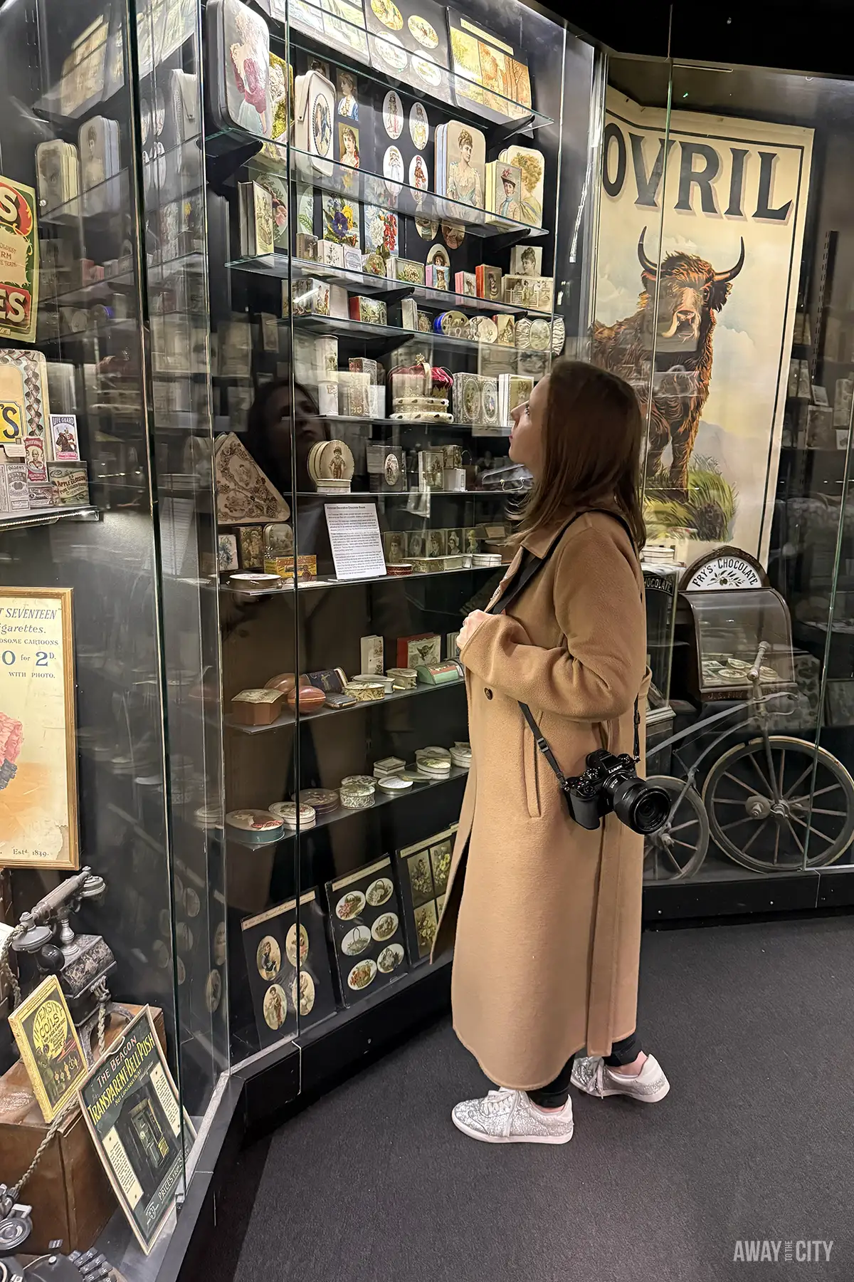 A woman looks closely at vintage tins and ephemera in a glass display case at the Museum of Brands in London, one of the city's best hidden gems.