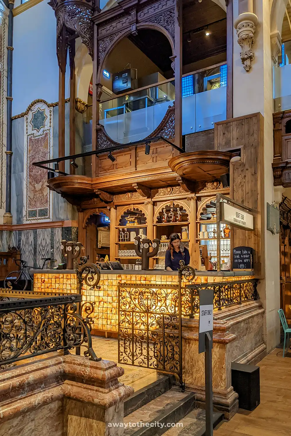 A busy bar with an ornate wooden frame is seen inside the Mercato Mayfair food hall.