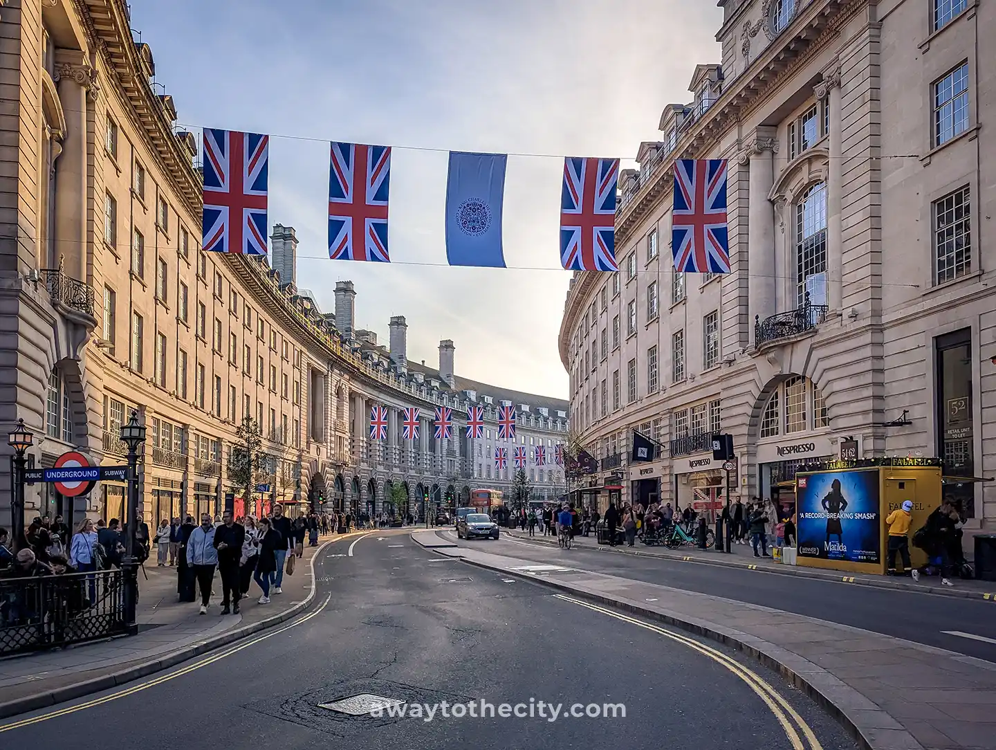 Regent Street is adorned with Union Jack flags and bustling with people on a clear day.