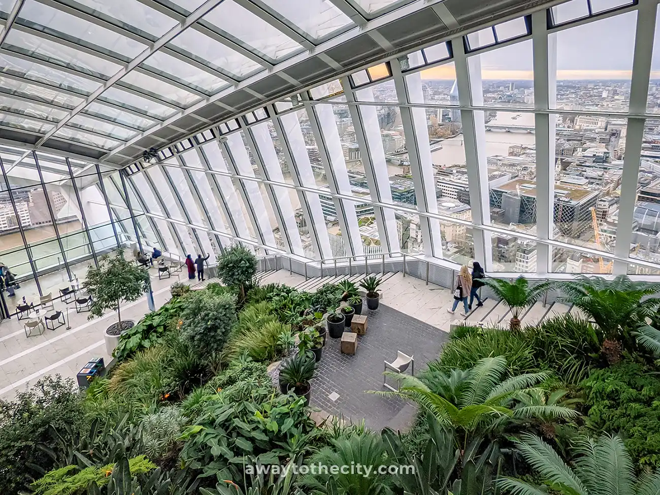A view from inside the Sky Garden in London, a public space with lush greenery and panoramic views of the city.