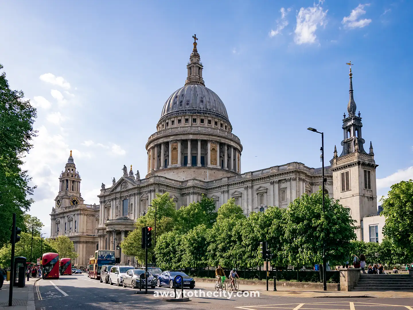  St. Paul's Cathedral stands grandly against a blue sky, with a busy street and cars in the foreground.