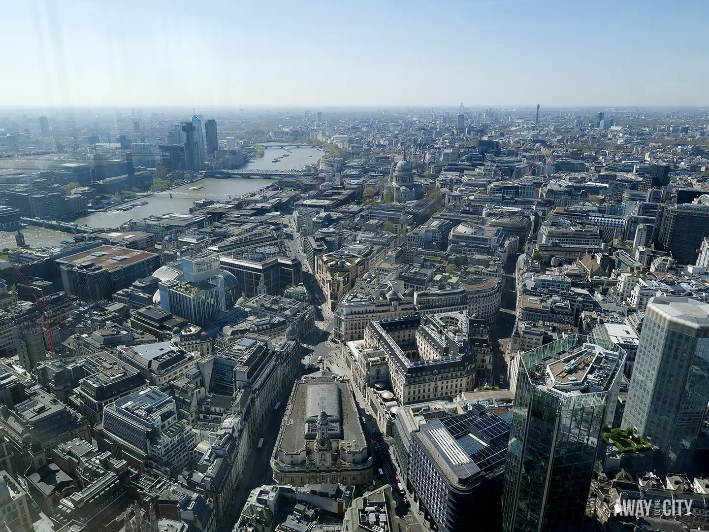 A stunning view of London's skyline, with the River Thames, St Paul's Cathedral, and a mix of historic and modern buildings under a clear sky.