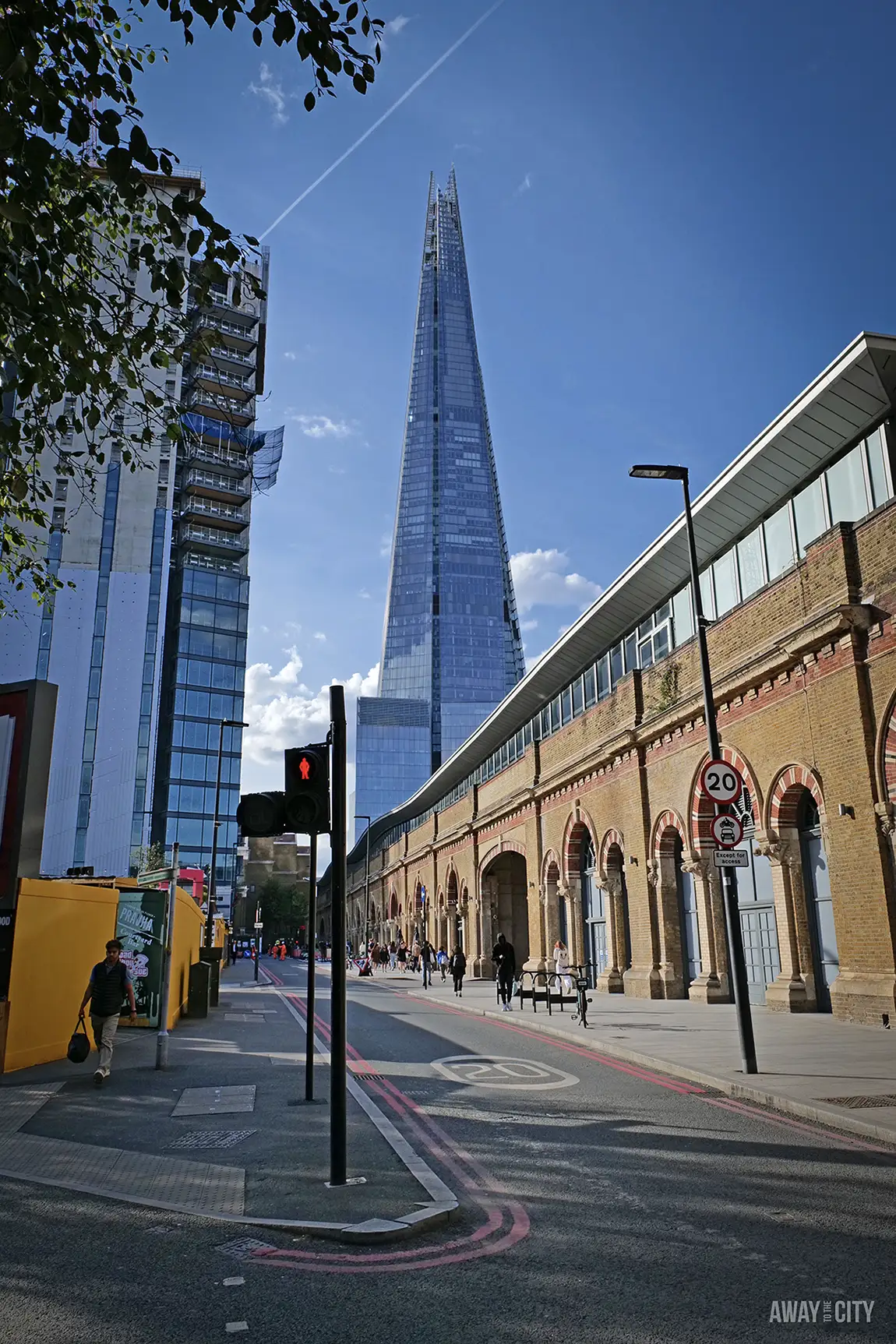 The Shard skyscraper rises into a blue sky from a London street.
