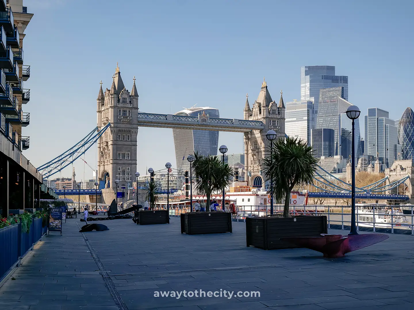 Tower Bridge is seen from Butler's Wharf pier, with modern city buildings in the background.