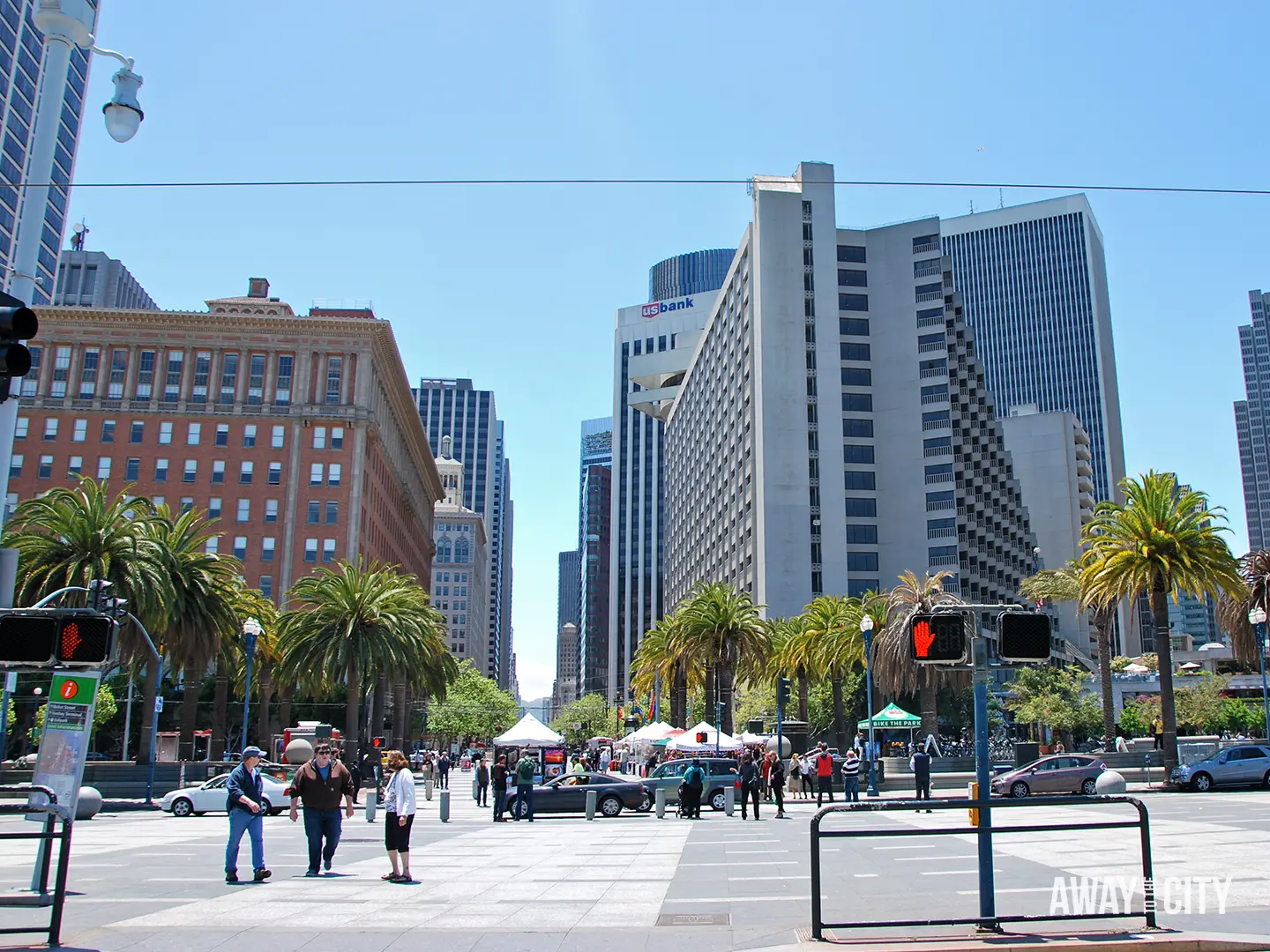 Union Square in San Francisco with palm trees, pedestrians and traffic, framed by downtown skyscrapers including the US Bank building.